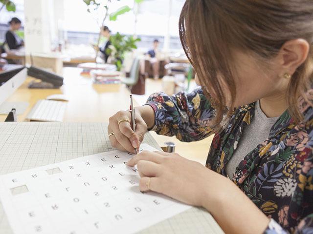 パソコンだけでなく実際に手を動かしながら作業するデザイナー。