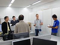 立ったまま打合せをするのが同社のスタイル。<br/>簡潔に、バイリンガルで進行する。