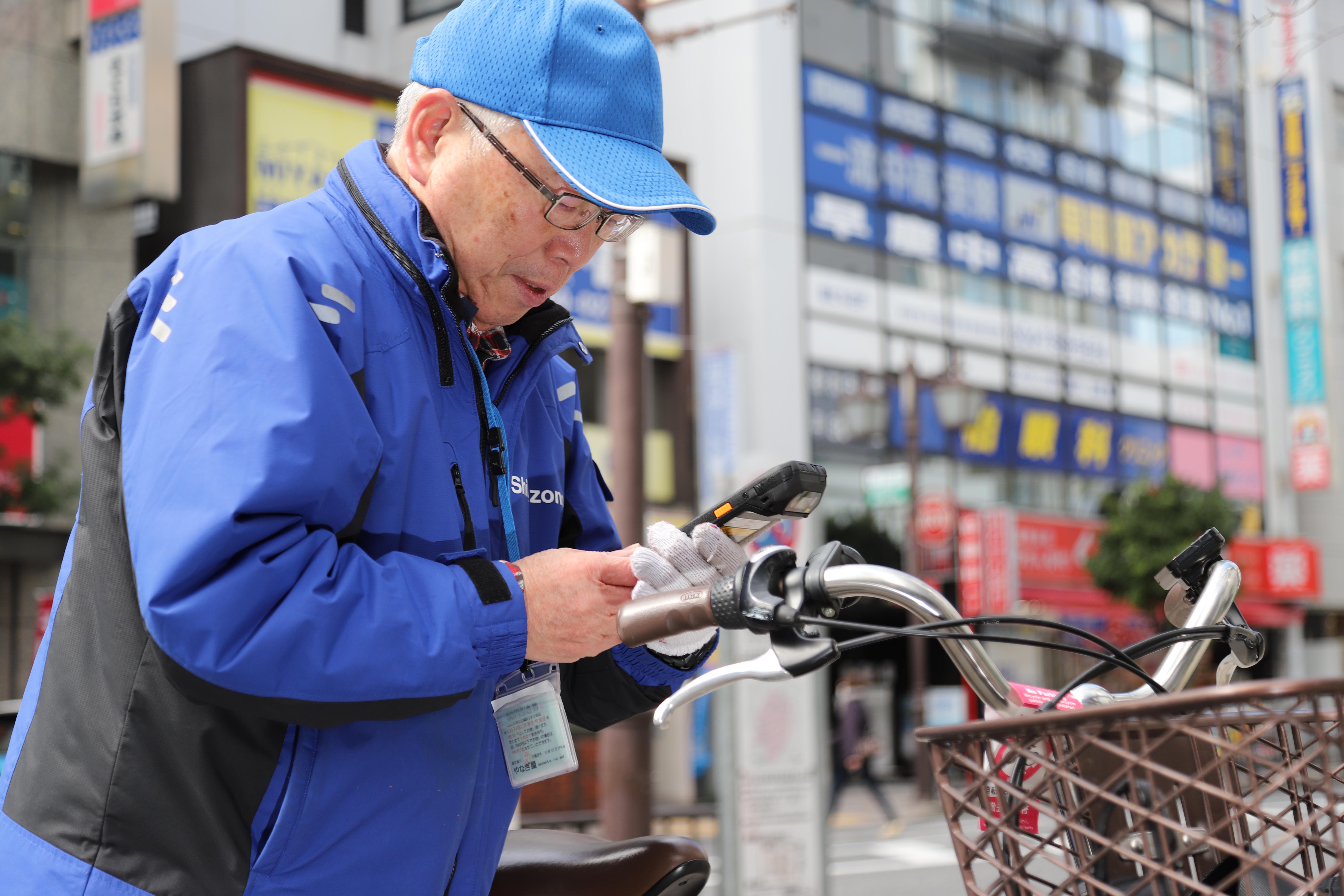 『Capture』システムを使って放置自転車の記録をする従事者。その多くは地域の高齢者の方々だ。システム開発担当者は「高齢者にも使えるシステムを」と心をくだき、各所に工夫をこらした。