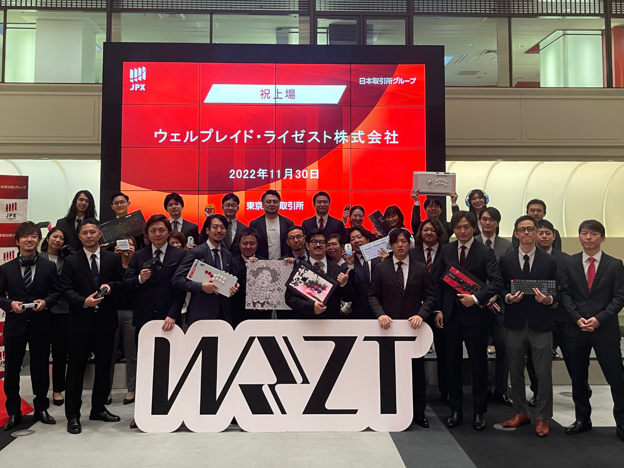 ウェルプレイド社とライゼスト社は、PC向けとコンシューマー・モバイル向けという“得意とするタイトル”の違い、そしてクライアントワークとコミュニティ運営という“強さを発揮できる事業領域”の違いを持っていた。そのため、合併後はeスポーツに関するビジネスの全方位をカバーする力を付けることができた。上場セレモニー時の記念写真では、それぞれが好きなデバイスを持って記念写真を撮影した